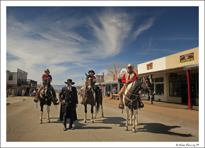 3 tourists on horseback pose with Wyatt Earp in downtown Tombstone