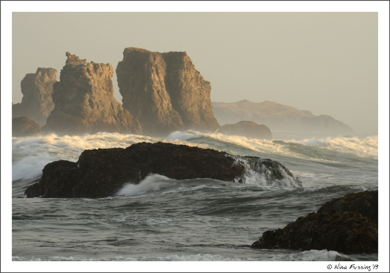 The low sun lights up waves by the sea stacks