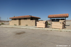 View of the facilities and trash in the gravel parking area.